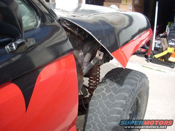 Modified truck fender with black and red paint, showing exposed suspension and large tire