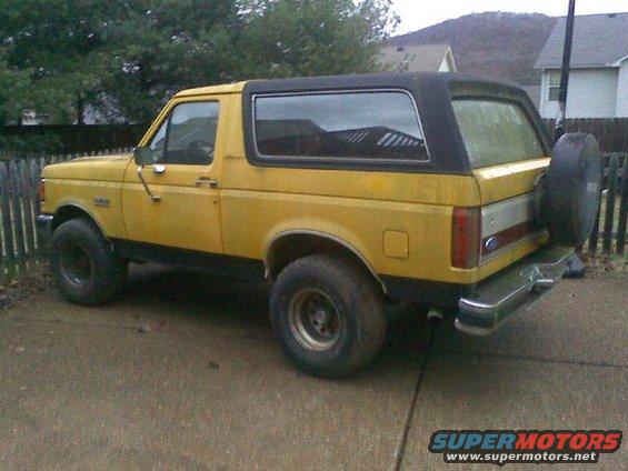 Yellow Ford Bronco parked on driveway, spare tire mounted on rear door