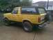 1988 Ford Bronco - This yellow Ford Bronco is parked outside next to a wooden fence.