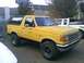 1988 Ford Bronco - A yellow 1988 Ford Bronco is parked outside next to a white pickup truck.