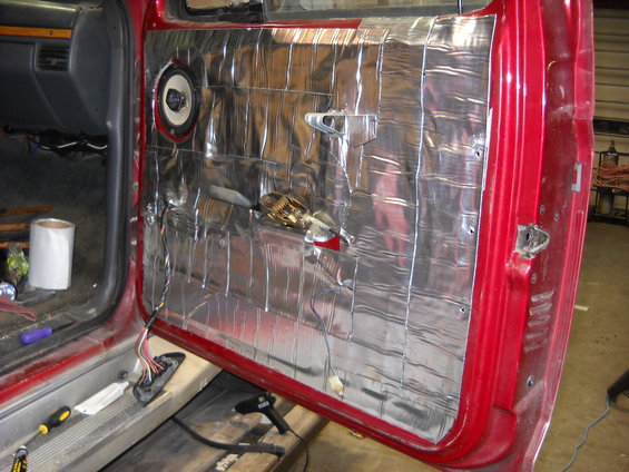 Interior door panel with sound deadening material and speaker
