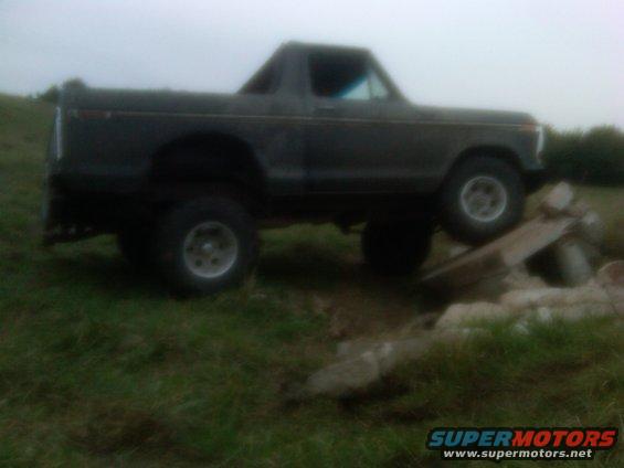1978 Ford Bronco on grassy terrain with one wheel on wooden planks