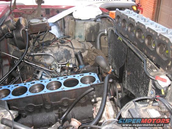 Engine block with blue gasket and detached cylinder head, radiator visible