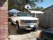 1994 Ford Explorer - A white Dodge pickup truck is parked in a driveway, elevated on concrete blocks.