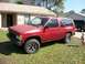 1994 Ford Explorer - A red SUV is parked on a grassy lawn in front of a house, with a child standing nearby.