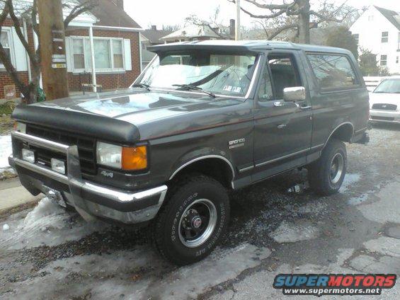 Dark gray Ford Bronco with a bug deflector and chrome bumper. It has 4x4 badging on the front fender