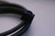 2003 Ford Taurus - A black wiring harness connector with a blue locking tab is shown against a light background.