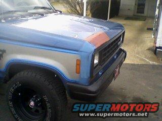Front corner of a blue and silver 1985 Ford Bronco II with an orange stripe on the hood