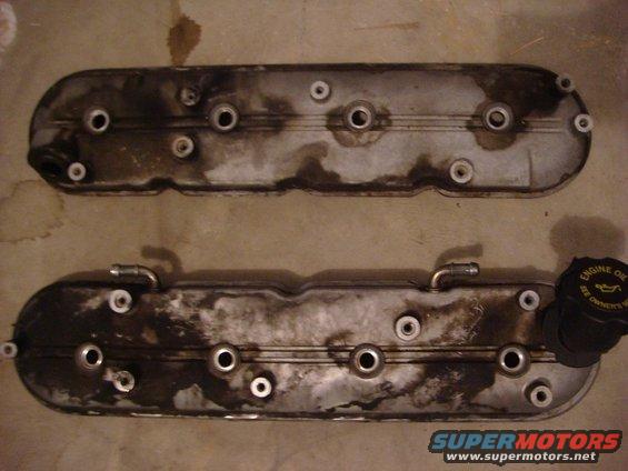 Two dirty engine valve covers, one with an oil cap that says 'ENGINE OIL SEE OWNER'S MANUAL'