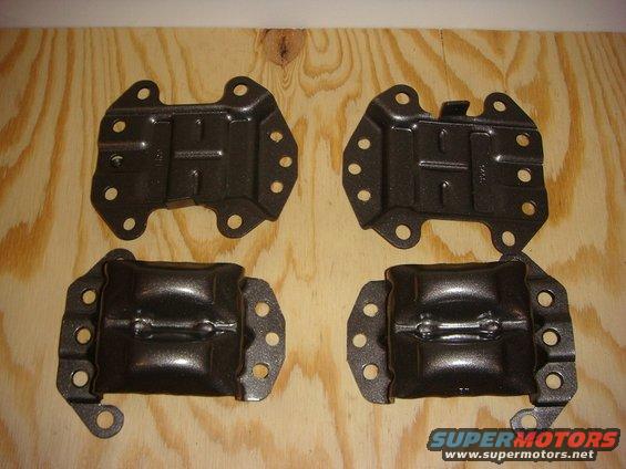 Four dark metal engine mounts on a wood surface