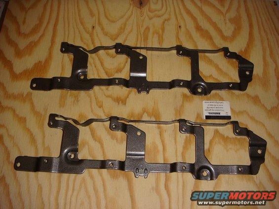 Two metal engine brackets on a wooden surface