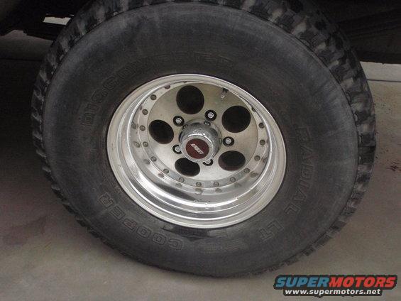 Close-up of a Cooper radial tire on a chrome alloy wheel with a red and silver center cap