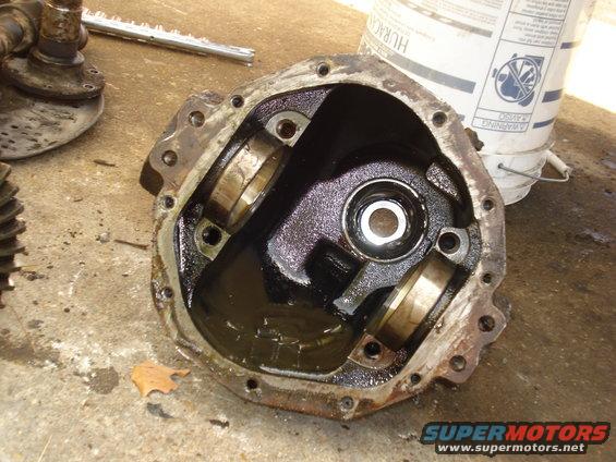 Differential housing with bearing caps removed, showing internal gears and oil