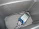 2003 Ford Taurus - An iPhone is plugged into a car accessory within a dark storage compartment.