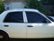 2002 Ford Crown Victoria - The side profile of a white 2002 Ford Crown Victoria sedan shows its tinted windows and black door handles.