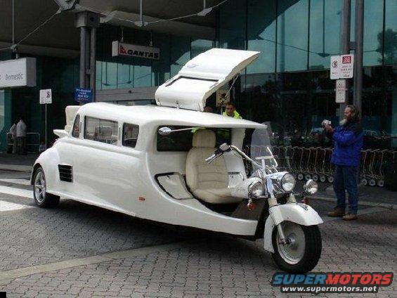 White custom limousine trike with motorcycle front, open roof compartment, and leather seats