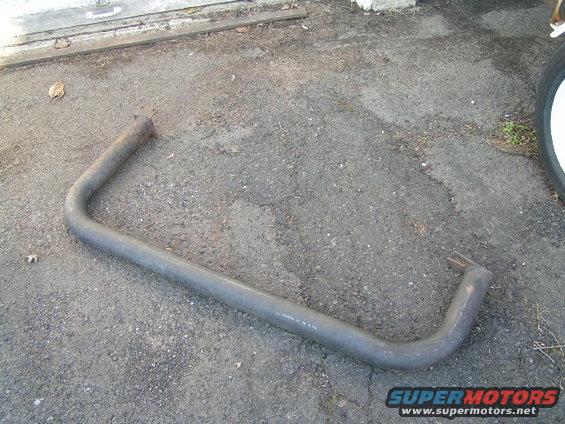 Gray metal exhaust pipe with two bent ends, lying on asphalt