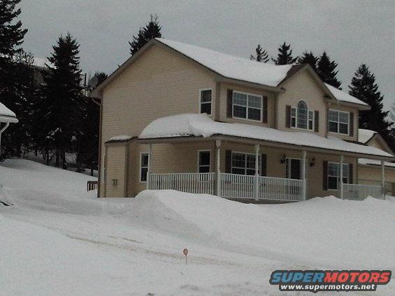 House covered in snow with trees in the background