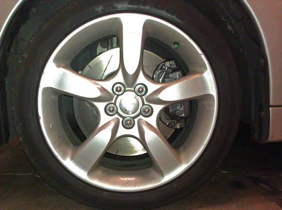 Close-up of a car's wheel, tire, brake rotor, and caliper