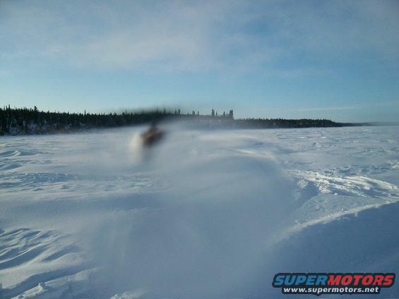 Snowmobile in motion on a snowy landscape with trees in the background