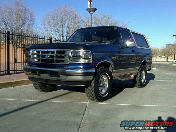 Blue Ford Bronco parked outside, front quarter view. Has a black hood protector