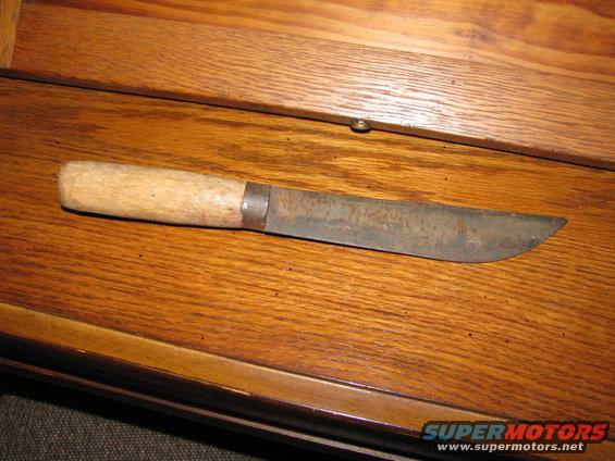Knife with wooden handle and rusted blade on wooden surface