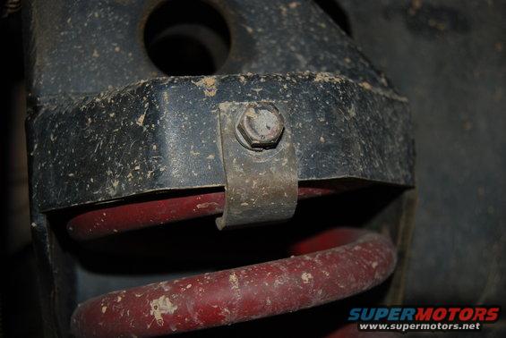 Close-up of a dirty suspension part with a red coil spring