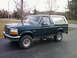 1993 Ford Bronco - A dark green 1993 Ford Bronco with a white removable hardtop is parked on a driveway.