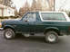 1993 Ford Bronco - A green 1993 Ford Bronco with a white removable top is parked on an asphalt surface.