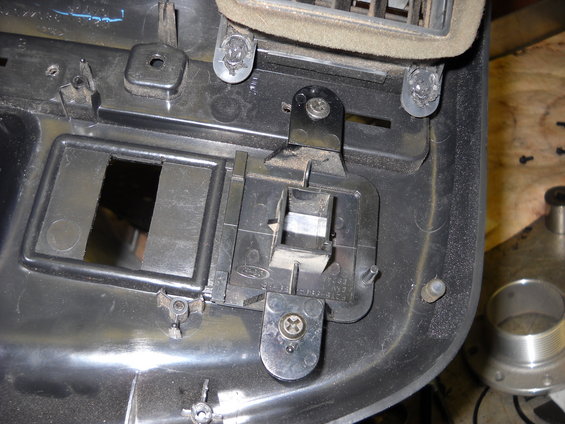 Close-up of a black plastic Ford dashboard component with a rectangular cutout and metal bracket attached