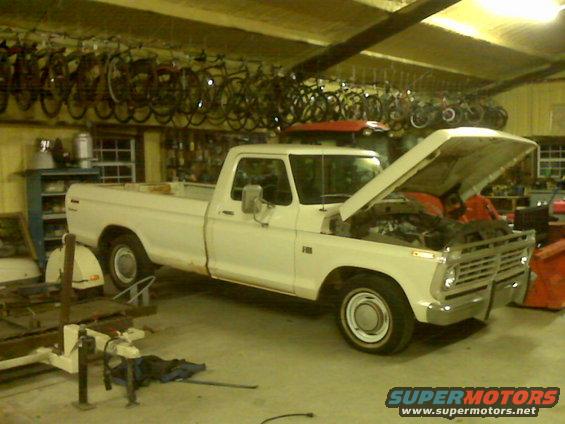 1973 Ford F-100 pickup truck in garage with hood open, showing engine