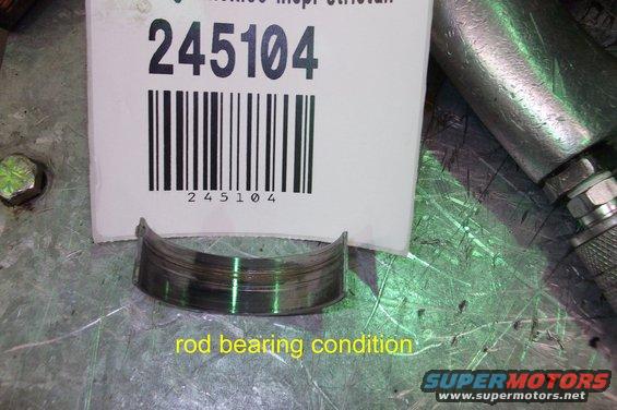 Rod bearing with visible wear marks, next to a barcode label with number 245104