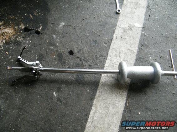 Slide hammer puller tool with adjustable jaws on a concrete floor