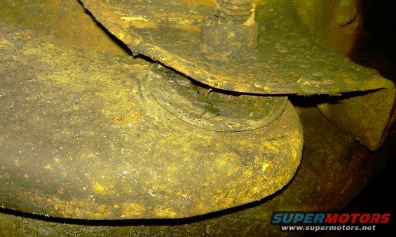 close-up of a heavily rusted metal suspension part with a bolt and nut