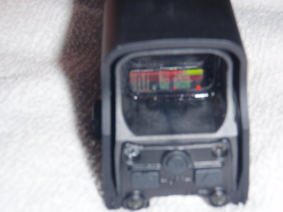 Black electronic sight with a digital display showing red and green bars