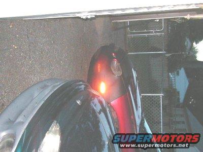 Rear of dark car with illuminated red taillight