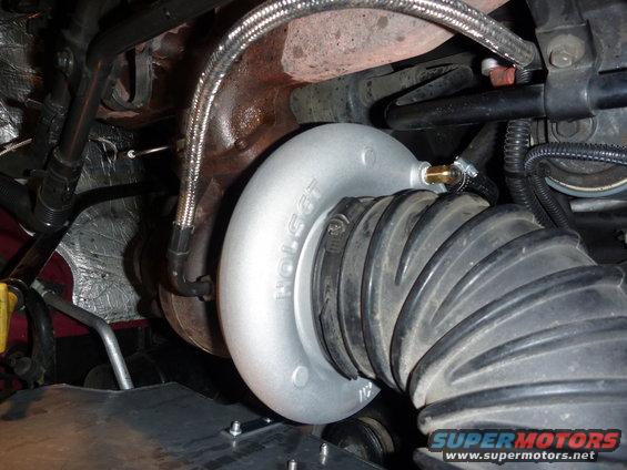 Holset turbocharger with silver housing connected to a black ribbed intake hose