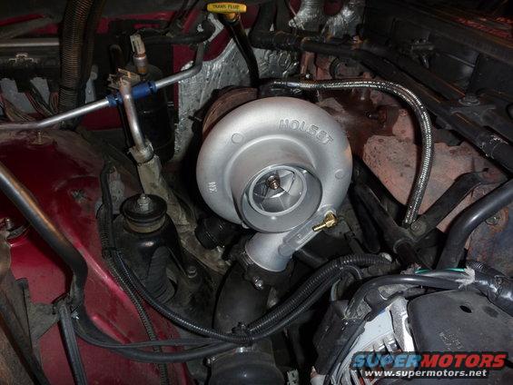 Engine bay with a silver Holset turbocharger, red fender, and black hoses