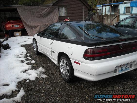 White coupe with black roof and spoiler, rear 3/4 view, snow on ground
