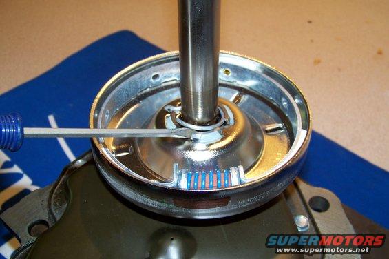 Chrome-plated washing machine part with a screwdriver, showing blue and red wire connectors