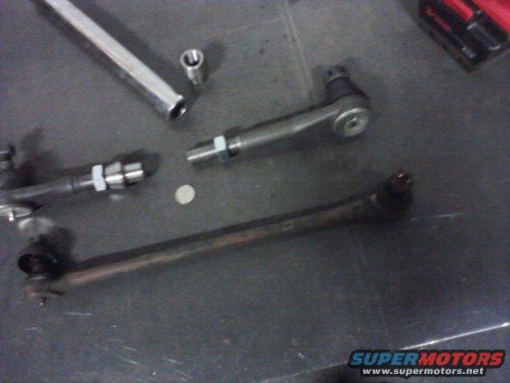 Tie rod ends and a socket wrench are laid out on a dark surface