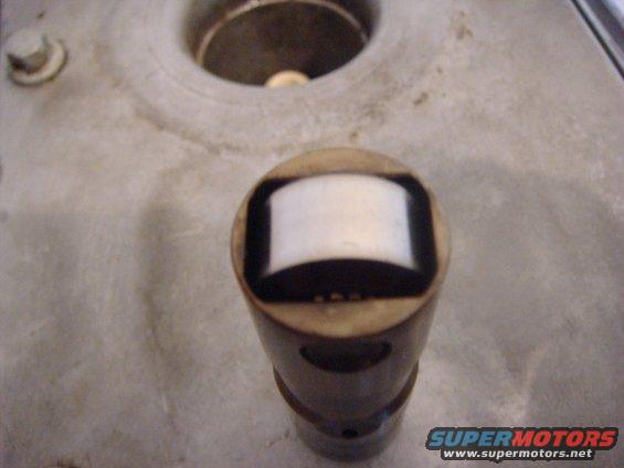 Close-up of an engine valve lifter with a white plastic insert
