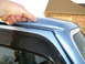 1995 Ford Bronco - Close-up of a blue SUV's roof showing chipped paint and a hand pointing to the damage.