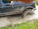 1991 Ford Bronco - This Ford F-250 is navigating a challenging muddy terrain, with water splashing around its tires.