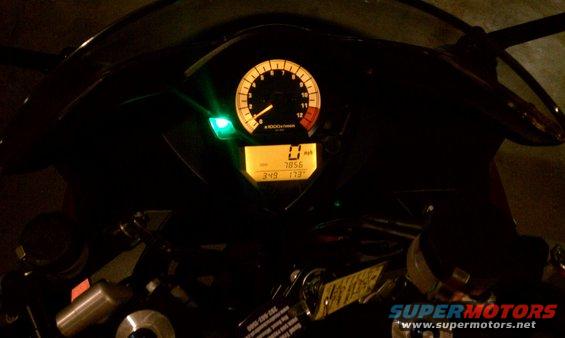 Motorcycle dashboard with illuminated tachometer and digital display showing 0 mph