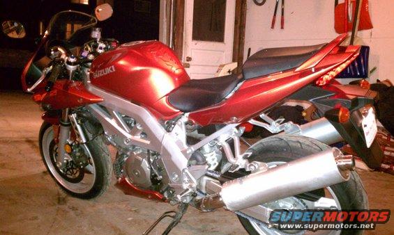 Red 2003 Suzuki SV1000S motorcycle parked indoors, showing its side and rear