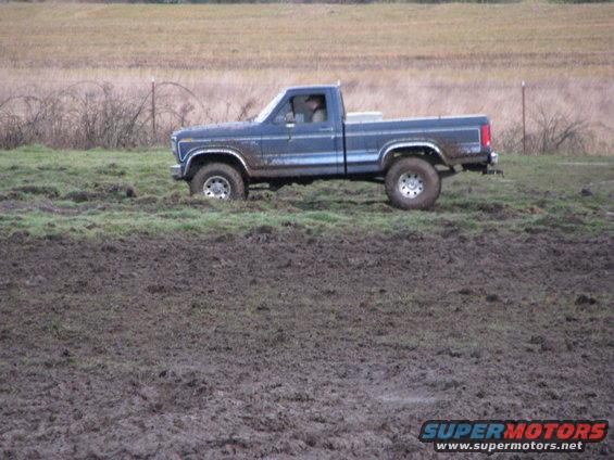 Blue pickup truck driving through a muddy field. It looks like a 1979 Ford F-Series