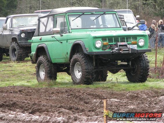 Green 1978 Ford Bronco with winch, parked in mud with another truck behind it