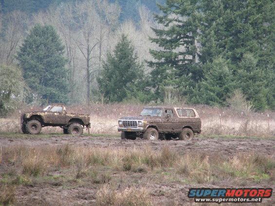 Mud-covered 1978 Ford Bronco and pickup truck in a muddy field