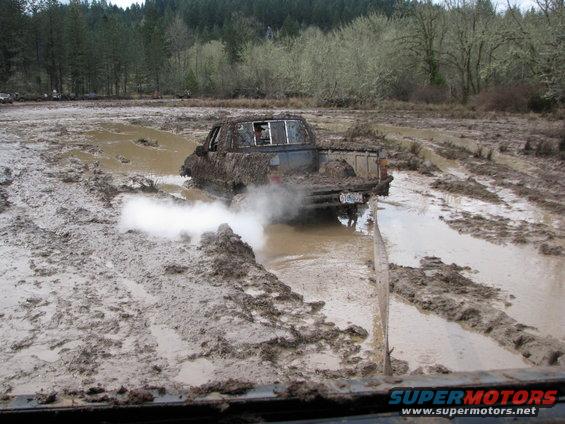 Pickup truck stuck in mud, kicking up white smoke